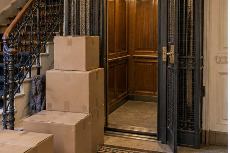 Cartons empiles devant un ascenseur d immeuble ancien de petite taille