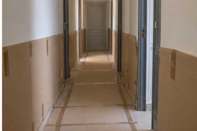 Couloir etroit protege par des plaques de carton au sol et aux murs