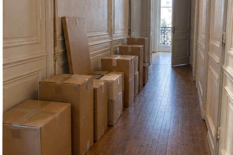 Cartons alignes le long du mur dans un couloir d immeuble