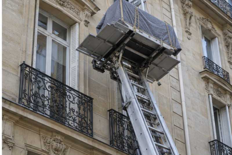 Monte meubles deploye le long d une facade en pierre de taille
