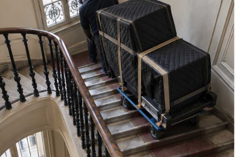 Piano droit sangle sur une luge dans une cage d escalier
